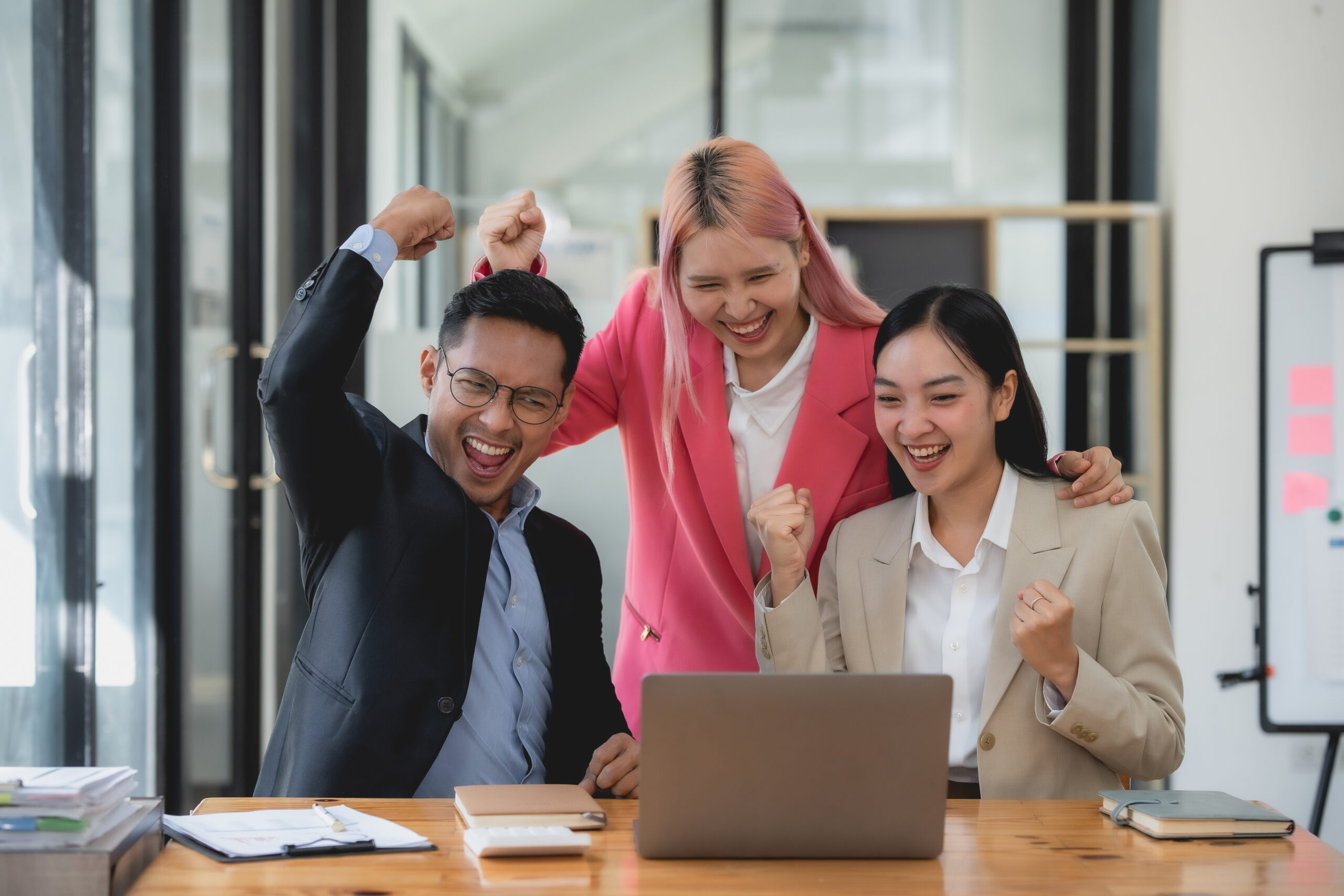 Three ecstatic asian business professionals celebrating a victor